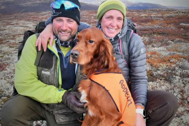 Hundekonkurranse-utøverne Rune Andrè Magnussen og Randi Halvorsen på tur med sin irske setter med oransje Appetitt-vest på høstvidda.